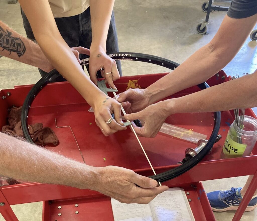 a bunch of hands working on a wheel